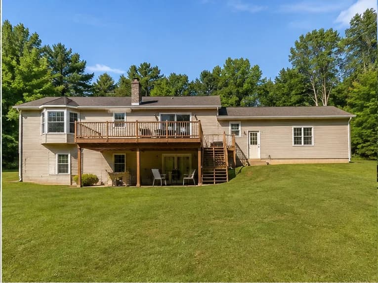 The back of the same house, with a raised deck above a covered patio.