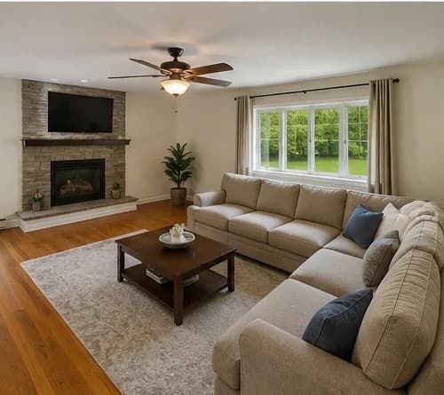 A living room with a stone fireplace and a sectional sofa.